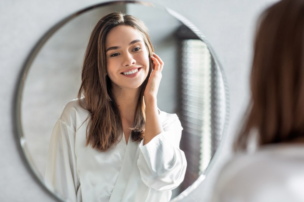 Woman looking in the mirror at her youthful look from PDO threads in Henderson, NV